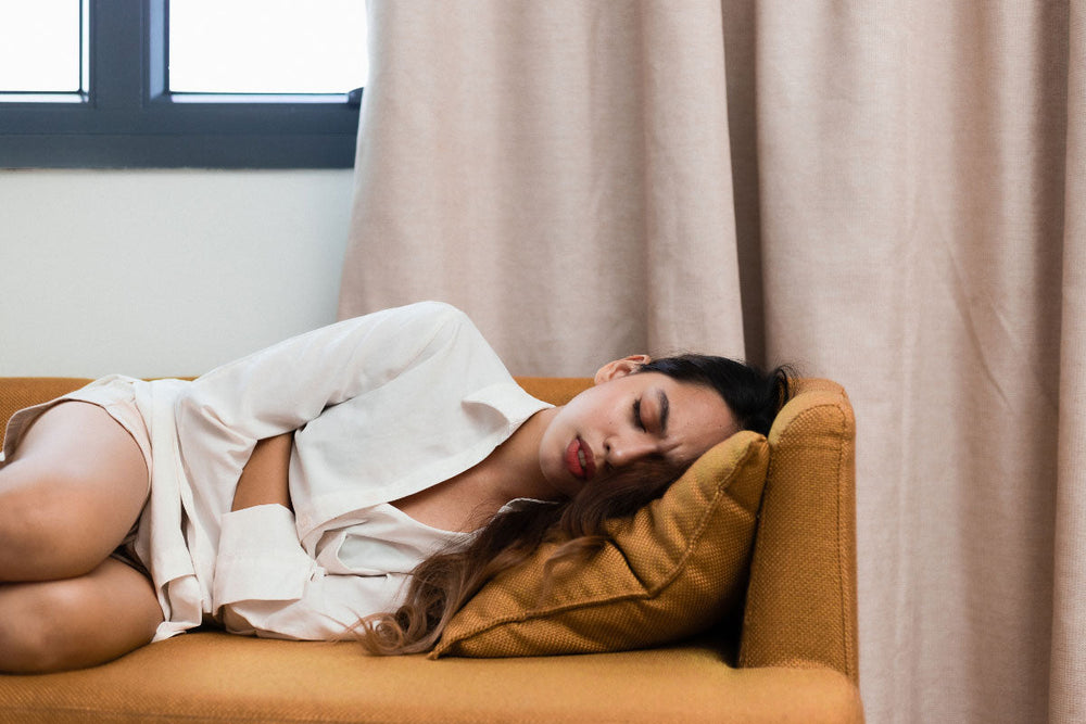 woman cringing in pain and laying down