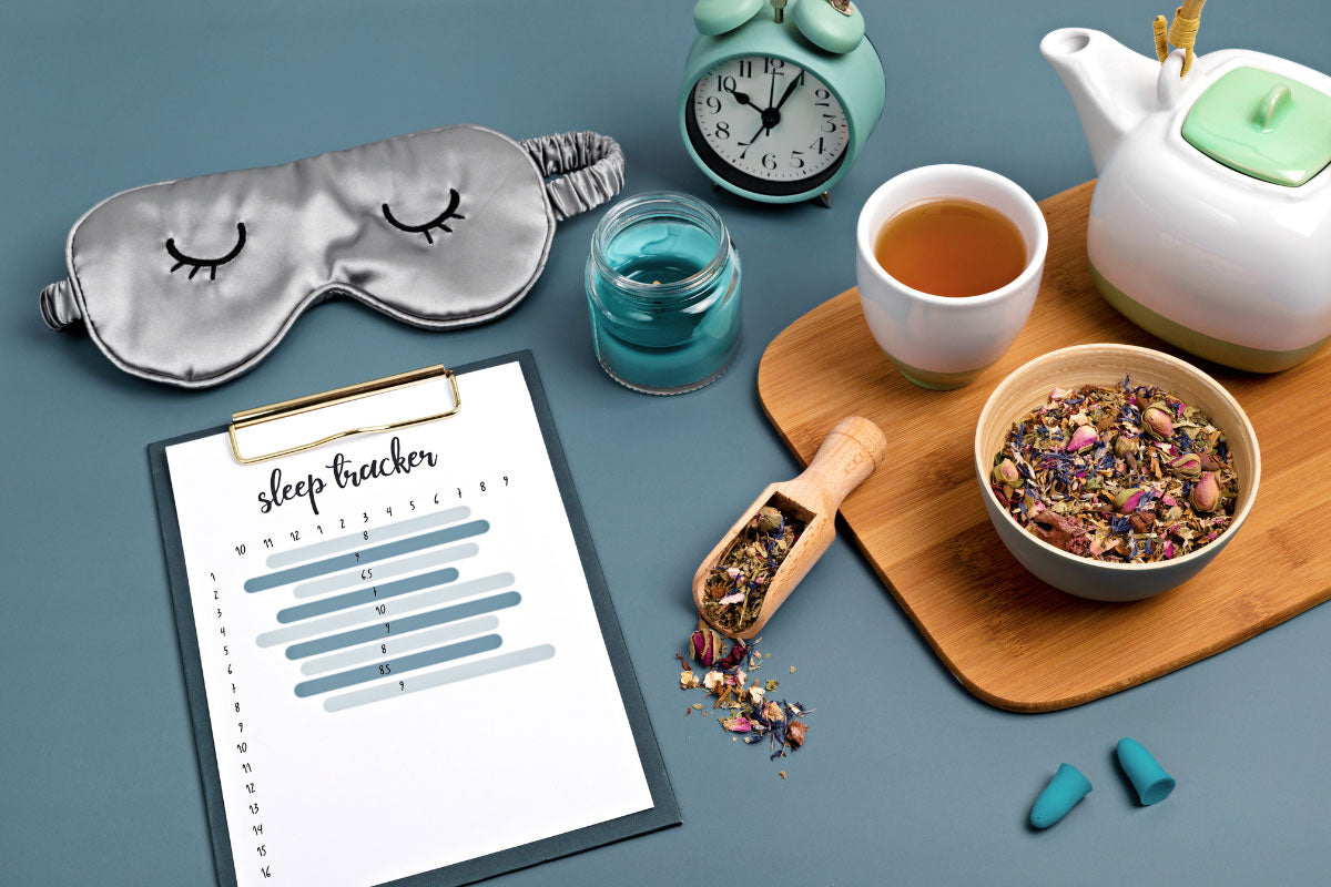 sleep mask, herbs, alarm clock, and sleep tracker on a table